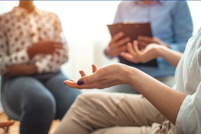 Close up of the hands of one person sitting in a group of three people